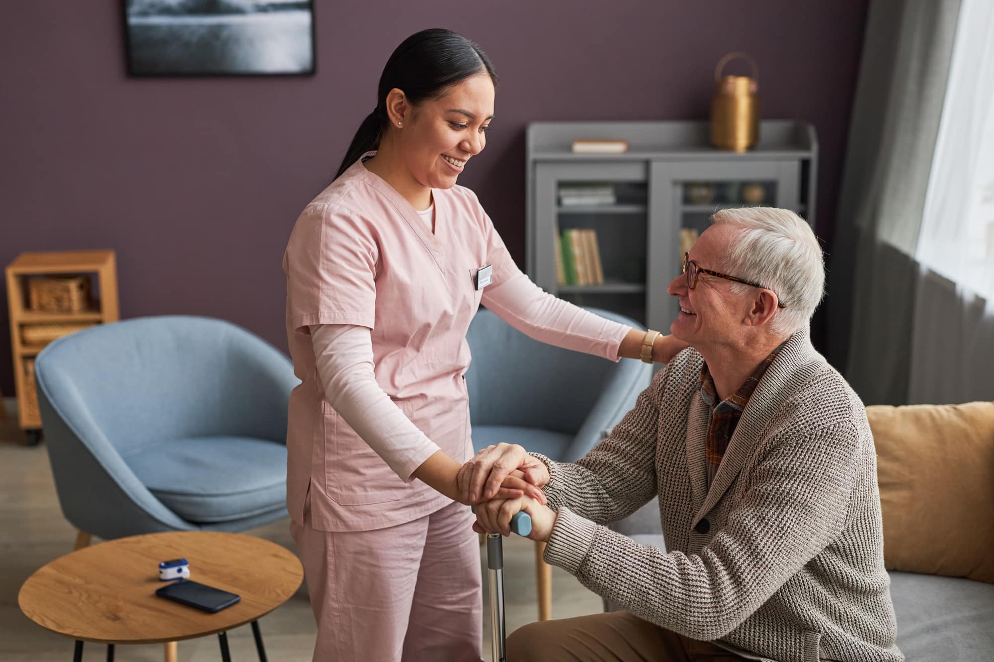Caregiver assisting an elderly man with mobility support during daily living activities