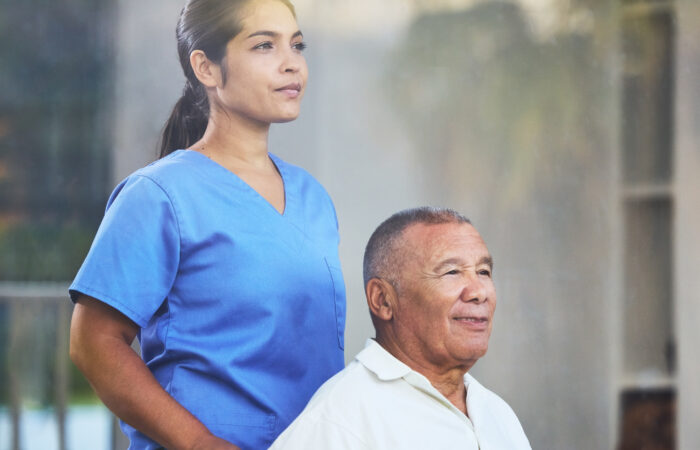 Home care nurse supporting an older adult in a wheelchair during daily living tasks