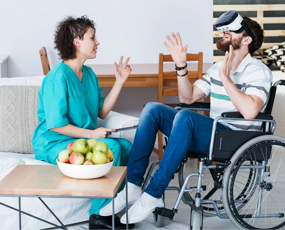 Therapist guiding a man in a wheelchair using virtual reality therapy at home