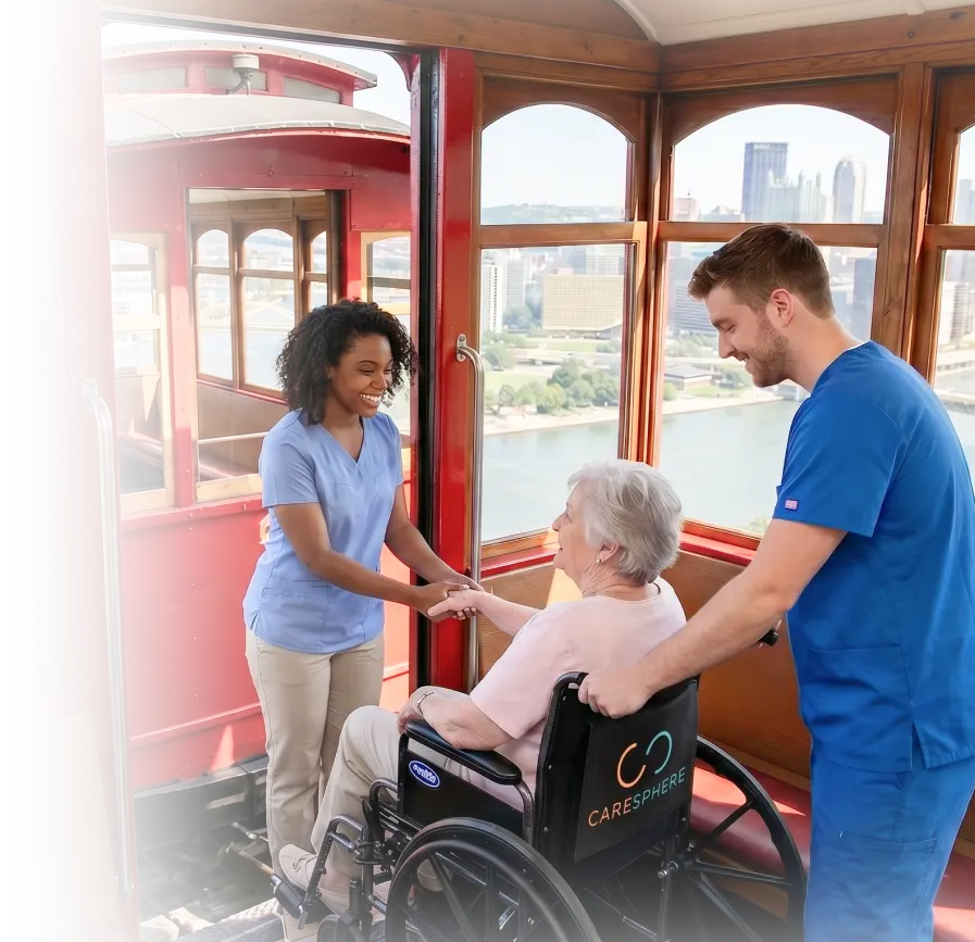 Two caregivers in scrubs assisting an elderly woman in a wheelchair inside a scenic cable car with a city view