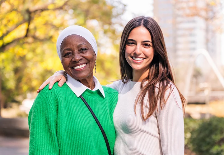 Caregiver providing companionship and support to a senior woman outdoors